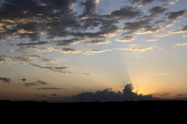 Kırsal kesimde gün doğumu. Bir gün doğar. Güneşin güneşin karanlıkla olan turuncu zıtlığı. Bu manzarayı güzel bir şey yapıyor. Siyah güneşle birlikte erir.
