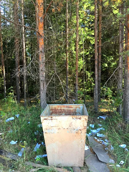 An empty trash can is in the forest