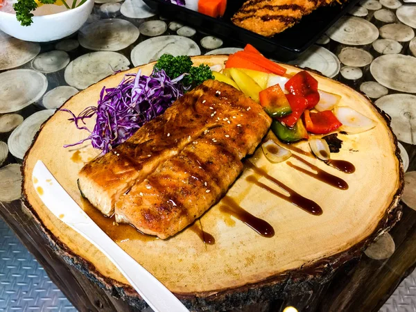Izgara somon biftek dilimleri. Barbekü, taze. Ahşap kesme tahtası, Lahana, dolmalık biber, ananas Beyaz susam üzerinde ızgara somon biftek dilimleri