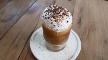 Latte macchiato kahvesi. Bir bardak kaşık, mum, peçete kahve çekirdeği ve ahşap bir masada kurabiyeli tabak.