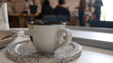 Kahve fincanı ve fincan tabağı kafede. Ahşap masa arkasında kahve fincanı manzarası. Kahve fincanı gri arka planda. Kafede kahve fincanı ve çay tabağı ve arka planda insanlar var.