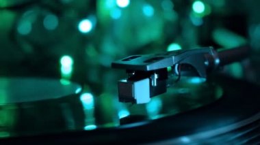 Vinil plak çalar. Pikap iğnesi düşer. Gece soğuk neon ışıkları arka plan.