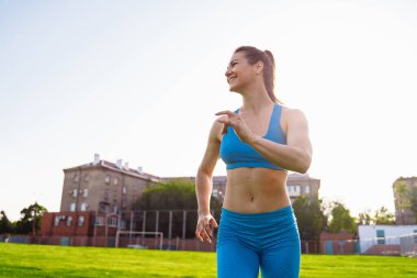 Genç profesyonel atlet kadın güneşli bir sabahta stadyumun yeşil çimlerinde koşuyor. Günlük hayatıyla mutlu. Her geçen gün koşusunun hızı artıyor..