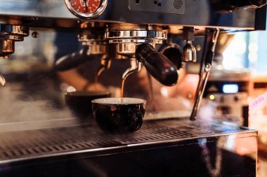 Bir restoranda, barda ya da barda kahve makinesinden espresso yapan baristanın yakın çekimi. Profesyonel kahve demleme. Kahve makineli Latte sanatı kafede buhar yapıyor. Klasik renk tonu.