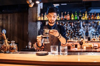 Yumuşak, sarı akşam lambası olan popüler bir kafede profesyonel bir barista, kahve çekirdeklerine metal çaydanlıktan sıcak su döküyor. Kahve yapmak için alternatif bir yol. Kahve filtresi.