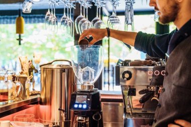 İyi bir restoranda profesyonel kahve öğütücüsü. İçine doğru düzgün öğütülmüş kahve dökülen bir tutacağa yakın plan. Öğütme, demleme metoduyla mükemmel eşleşiyor.