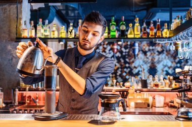 Yumuşak, sarı akşam lambası olan popüler bir kafede profesyonel bir barista, kahve çekirdeklerine metal çaydanlıktan sıcak su döküyor. Kahve yapmak için alternatif bir yol. Kahve filtresi.