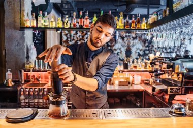 Kahve demlemek için alternatif bir yöntem. Baskı makinesiyle kahve yapan çekici, genç bir barista. Nazikçe şişeye bastırır ve kahve sıvısını filtreden geçirir. Sütsüz ve şekersiz kahve.