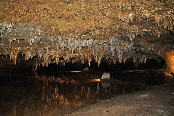 A spring of water that has an almost mirror-like appearance. Stalactites reflected in the water appear to be stalagmites, an illusion so convincing that people are unable to see the real bottom.