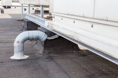 Endüstriyel bölgedeki yüksek bir binanın çatısında vantilatörler var.