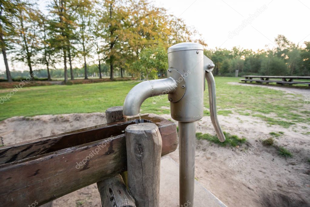 in a park there is a wooden waterfall with a water pump