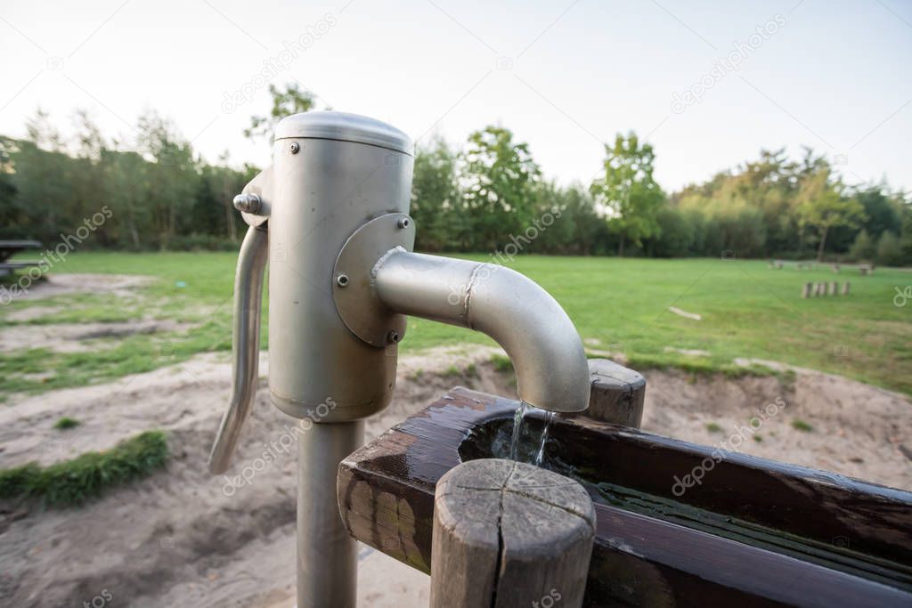 in a park there is a wooden waterfall with a water pump