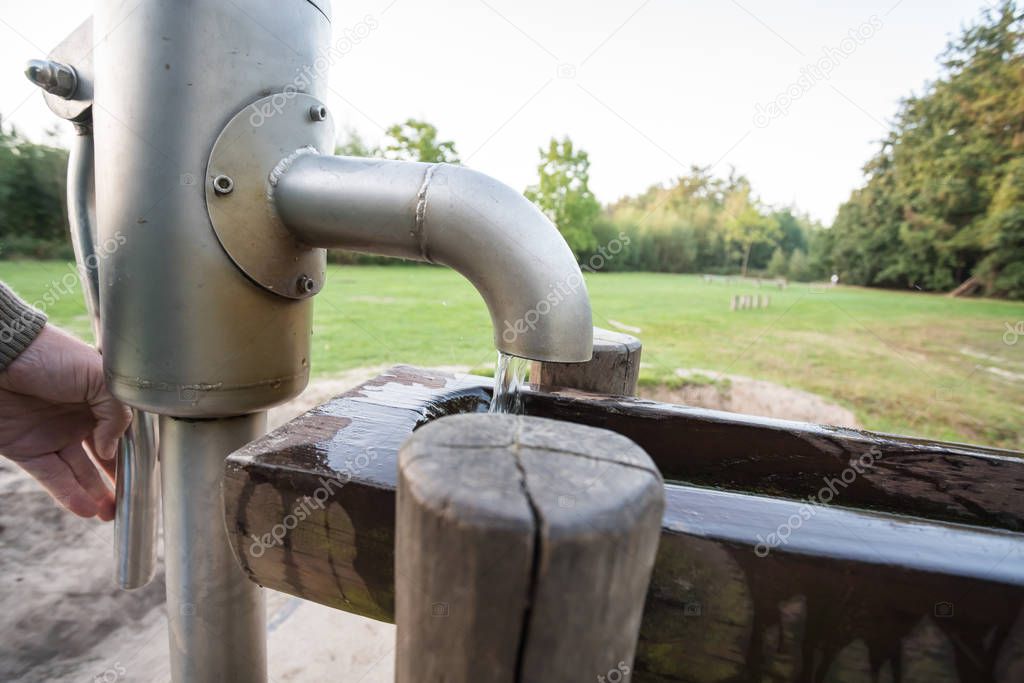 in a park there is a wooden waterfall with a water pump