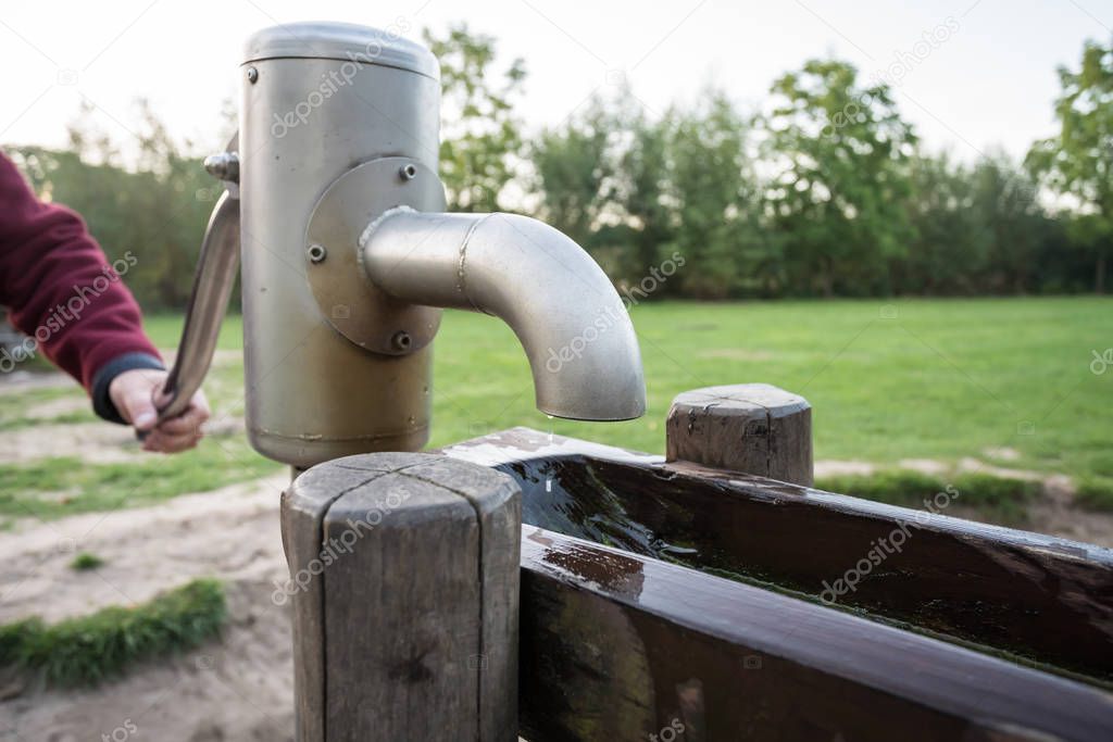 in a park there is a wooden waterfall with a water pump