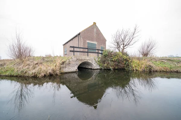 along a river that crosses the field there is a house