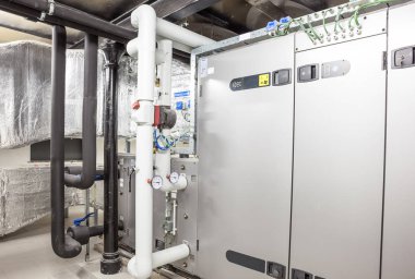 Büyük bir binanın bodrumundaki teknik bir odada uzun bir havalandırma borusu.