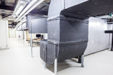 Büyük bir binanın bodrumundaki teknik bir odada uzun bir havalandırma borusu.