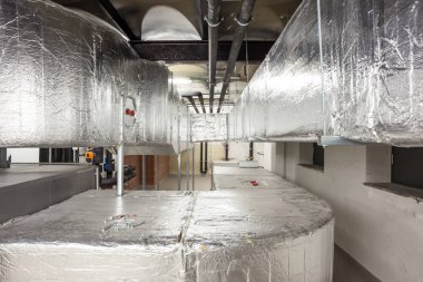 Büyük bir binanın bodrumundaki teknik bir odada uzun bir havalandırma borusu.