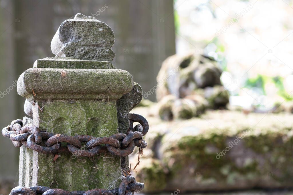 In a cemetery or cemetery, there is a skull with moss on a gravestone and an Rusty steel chain.