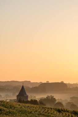 Güneşli bir Eylül sabahı, bu güzel Rozebeke kilisesi yükselen güneşle sisin içinde duruyor..
