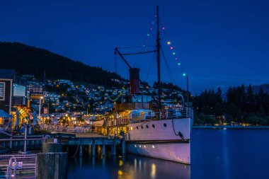 Modern gemi ayakta karanlık akşam tarihinde South Island, Yeni Zelanda ışıklı yerleşim pier yakınındaki