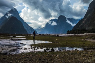 Muhteşem dağ ve bulutlu gökyüzü arka plan üzerinde ıslak vadinin ortasında duran tanınmaz kişi silüeti