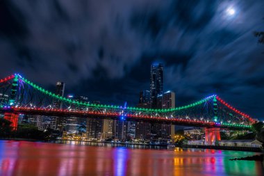 Bulutlar üzerinde karanlık gökyüzü parlak ışıklı köprü ve gökdelenler Brisbane, Avustralya üzerinde yüzen bir kadeh aşağıdan