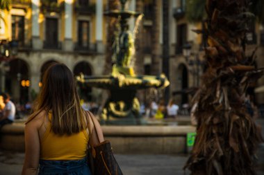 Genç bayanın Çeşme Barcelona güzel şehir meydanında yürürken arkadan görünüm