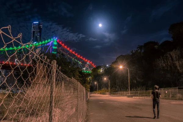 Back View Anonymous Guy Walking Empty Road Metal Fence Illuminated — Stock Photo, Image