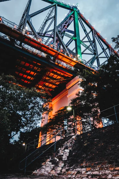 Brückenkonstruktion Aus Metall Mit Hervorgehobenen Roten Säulen Und Grünen Bäumen — Stockfoto
