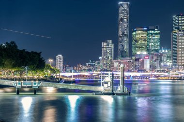Gece Brisbane ile birçok ışık ve ışıklandırılmış gökdelenler ile modern şehir bina ve yeşil bitki örtüsü ile vurgulanan pier
