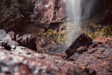 Et doğal görünüm altındaki yeşil çalılar ile Kanyon ve çim dere ile şelale altında kahverengi taş