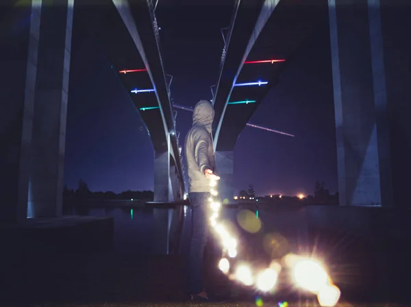 Anonymous Man Holding Burning Garland Standing Modern City Bridge Night — Stock Photo, Image