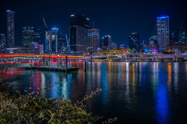 美丽的城市景观与高耸的霓虹灯反射在平静的都市河水在夜间时间 — 图库照片