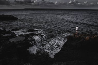 Muhteşem deniz manzarası ve güçlü dalgalar aşağıdaki yüksek uçurumun üzerinde ayakta anonim adam görünümünü