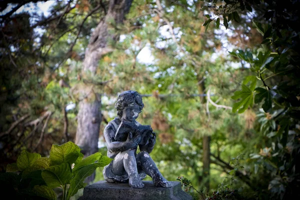 a sculpture of a boy reading a book beneath the trees, rich green colors, idyllic and calm landscape