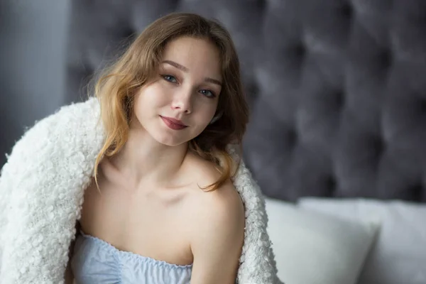 Yatak yatak odasında sabah oturan genç kadın — Stok fotoğraf