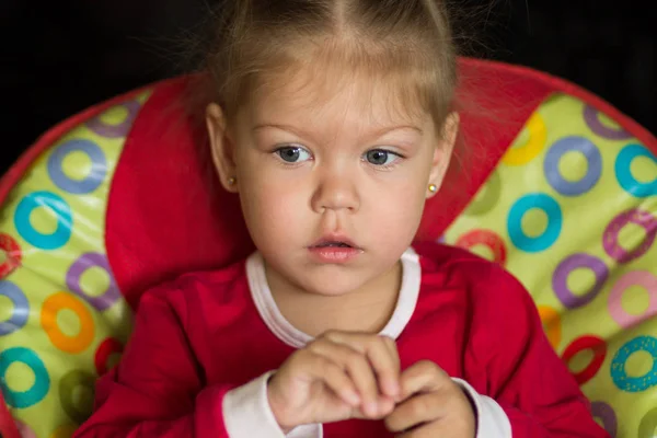 Retrato de niña con mirada pensativa sentada en la silla de alimentación —  Fotos de Stock