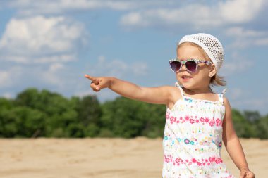 Güneş gözlüğü küçük kız parmak elini bir kenara işaret ve kenara bakıyor