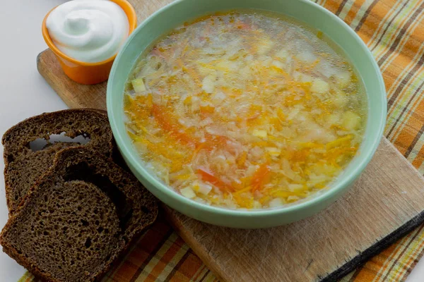 Tradycyjna zupa Rosji Shchi podawane z kwaśną śmietaną jako ozdoba i chleb żytni — Zdjęcie stockowe