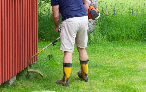 Hombre siega hierba verde en el césped de verano — Foto de Stock