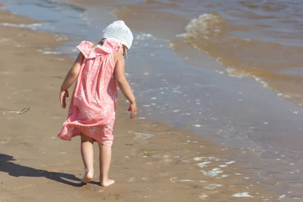 Espalda de niña en la playa de verano bañada por las olas — Foto de Stock