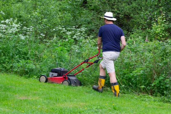 Hombre cortando el césped verde en el parque de verano — Foto de Stock