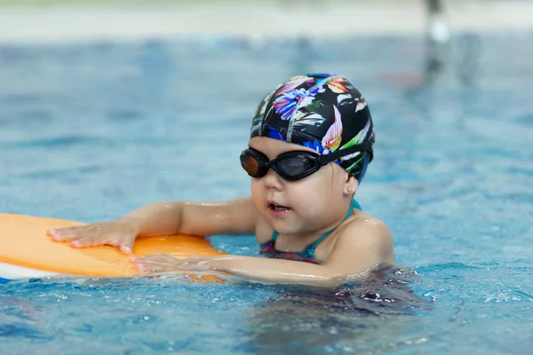 Menina com placa flutuante na piscina — Fotografia de Stock