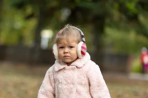 Bella e incerta bambina nel parco autunnale guardando la fotocamera — Foto Stock