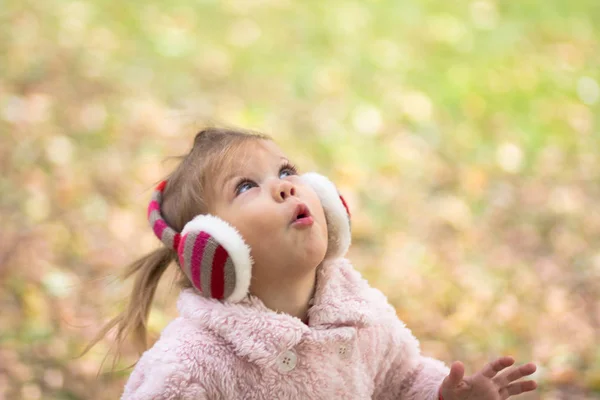Hermosa chica sorprendida lttle mirando hacia arriba en el parque de otoño —  Fotos de Stock