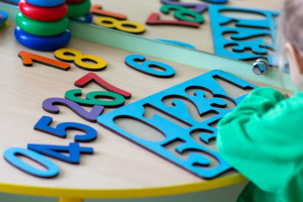 Anaokulu bahçesinde çok renkli ahşap sayı bulmaca ile oynayan çocuk