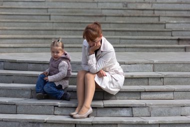 Çocuk ve anne merdivenlerde oturup birini bekliyor