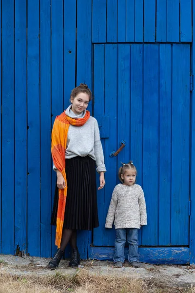 Wanita muda dan anak-anak dengan latar belakang kayu biru melihat kamera — Stok Foto