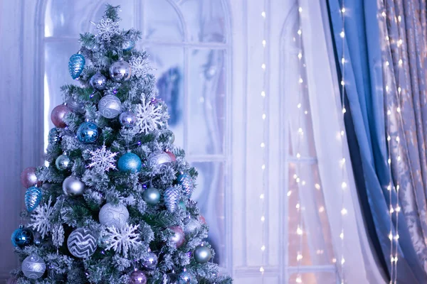 Mavi tonlu mavi toplar ve kar taneleri ile süslenmiş Noel ağacı